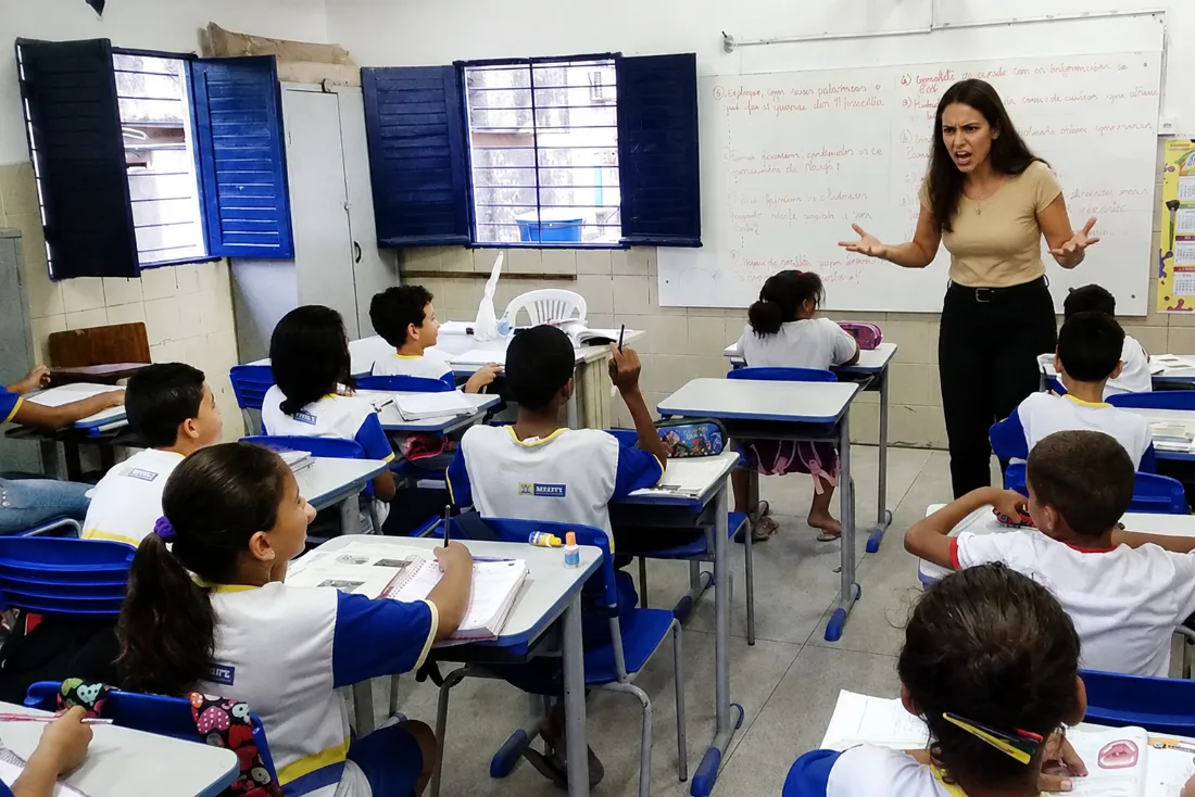 Professora tentando dar aula em uma sala cheia de alunos agitados